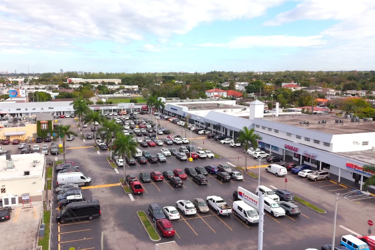 Aerial of a strip center and its parking field along a busy commercial corridor
