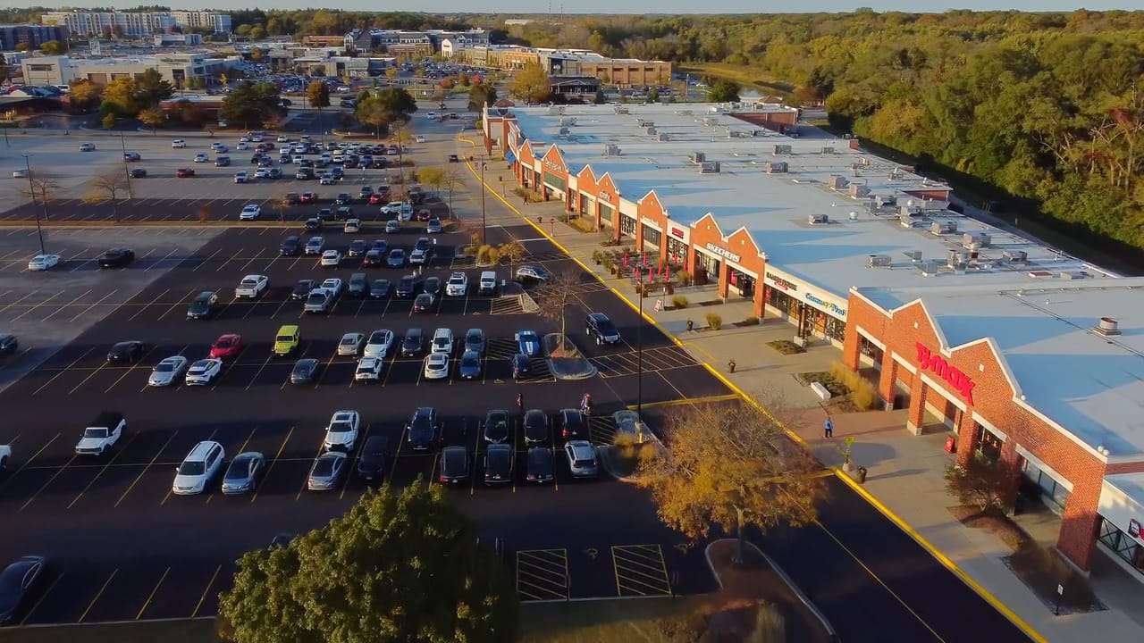 Aerial of a multi-tenant retail center at golden hour, with its storefronts and parking field