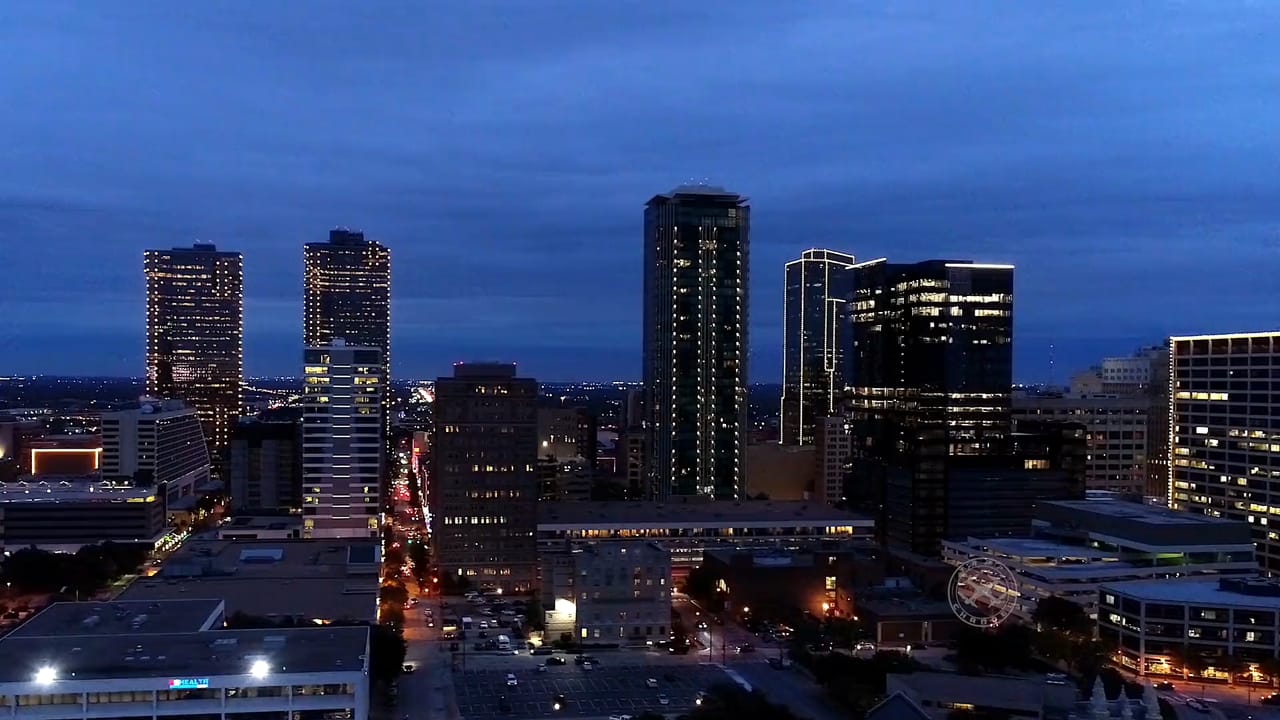 Downtown Fort Worth from the air at dusk, with the skyline lit against a deep blue sky